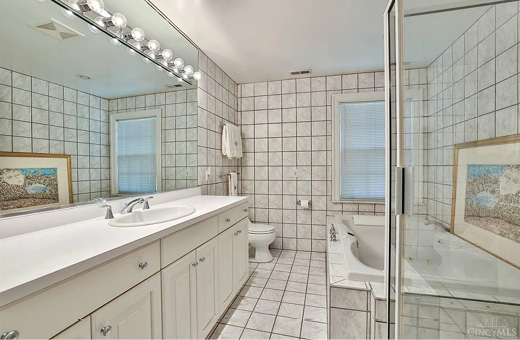 Existing bathroom before the renovation: dated white tile and a long vanity