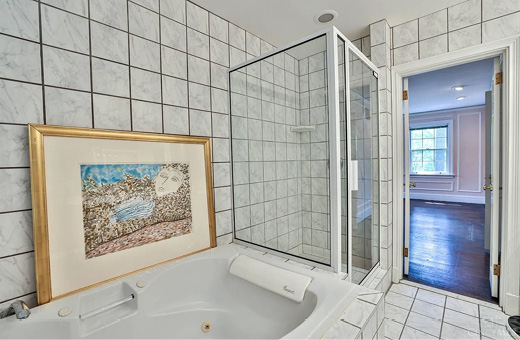 Existing bathroom before the renovation: corner tub and framed shower in white tile